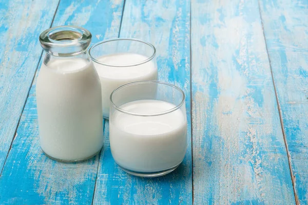 Eine Flasche Milch und ein Glas Milch auf einem blauen Holztisch, — Stockfoto