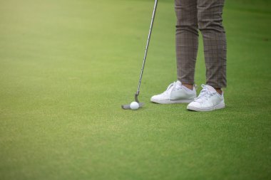 Golf oyuncu Yeşil ve Golf Ball Yakın Hole koyarak.