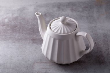 Çaydanlık kreması, fincan ve çay tabağı çimento tahtasında.