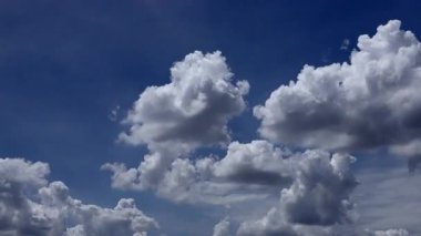 Mavi gökyüzünde hareket eden kabarık bulutlar ve beyaz kümülüs bulutları