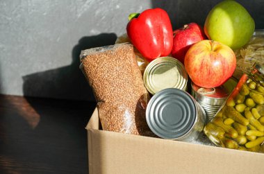Çeşitli yiyeceklerle birlikte bağış kutusu. Tereyağı, konserve, mısır gevreği ve meyveli karton kutuyu aç.
