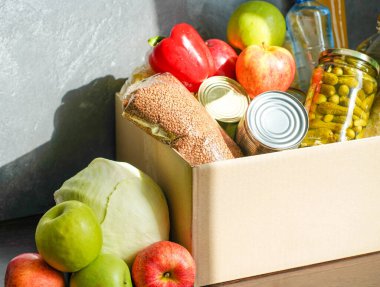 Çeşitli yiyeceklerle birlikte bağış kutusu. Tereyağı, konserve, mısır gevreği ve meyveli karton kutuyu aç.
