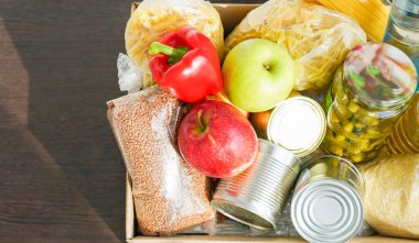 Çeşitli yiyeceklerle birlikte bağış kutusu. Tereyağı, konserve, mısır gevreği ve meyveli karton kutuyu aç.