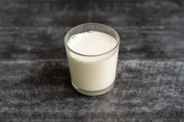 Siyah arka planda bir bardak beyaz süt..