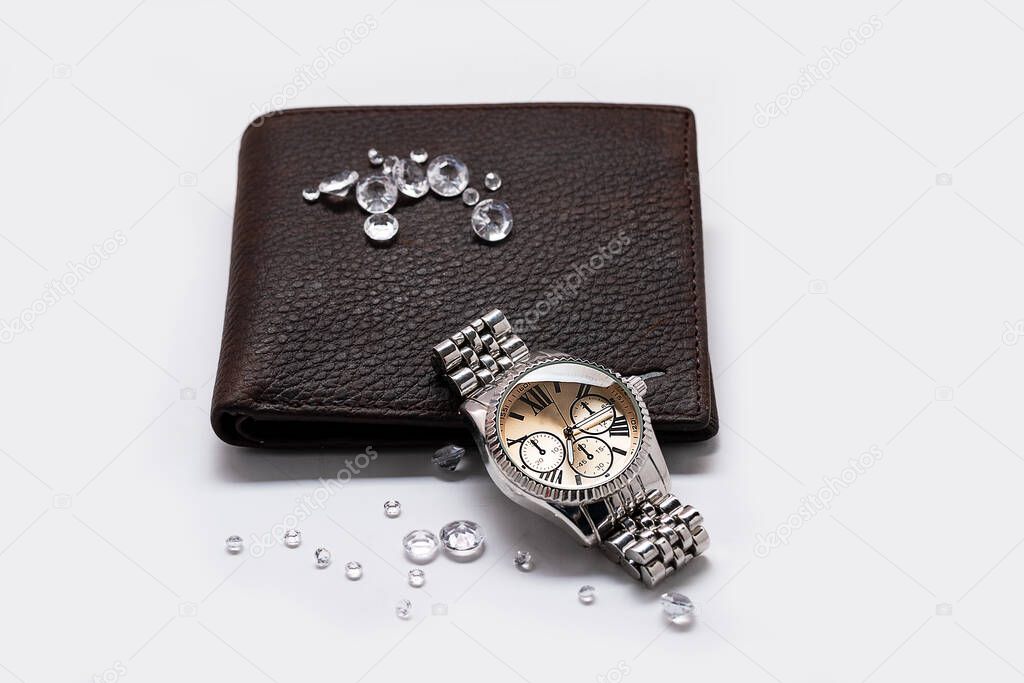 Brass knuckles and golden watch between crystal diamonds on men's wallet, closeup with selective focus.The concept of robbery and mafia. luxury