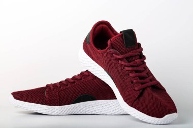 Modern kırmızı erkek spor ayakkabılarının ön tarafında koşmak için yüksek açı var. Beyaz arkaplanda yakın çekim.