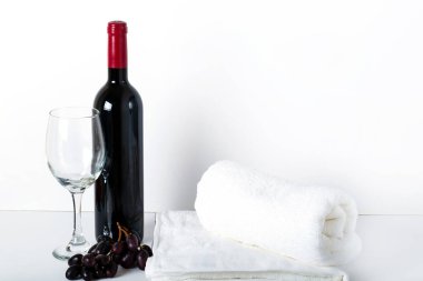 Kırmızı şarap, şarap bardakları ve beyaz arka planda beyaz havlular ve aşık kalpler. Otelin yatak odasındaki beyaz arka plana güzel beyaz havlular yerleştiriliyor..