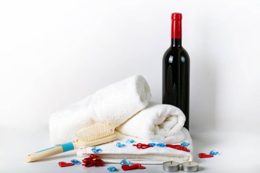 Kırmızı şarap, bir demet üzüm, beyaz saplı saç fırçası otelin yatak odasında havlular ve beyaz arka planda tasarım ve dekorasyona aşık kalpler.. 