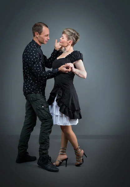 Beauty couple dancing on grey background. Dance and love concept. Two dancers man and woman holding each other in passionate pose.
