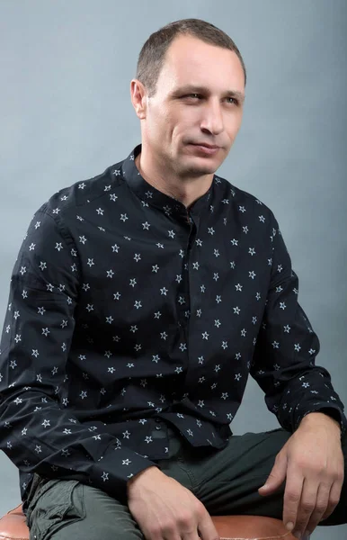 Привлекательный Молодой Человек Черной Рубашке Сидит Стуле Смотрит Серый Фон — стоковое фото