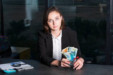 Bir tomar para tutan ve gösteren bir iş kadını, İsrail para banknotları şekekliyor. Finansal tema.