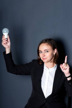 Kız bir elinde ampulü tutuyor, diğer elinde de parmağını havaya kaldırıyor.