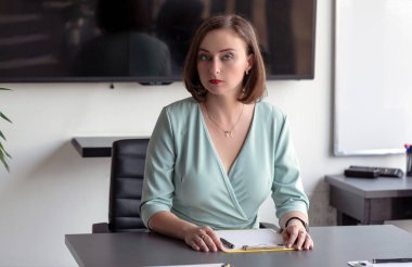 Ofisteki bir masada otururken bilgisayarın üzerinde çalışan güzel esmer kadın.