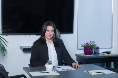 Ofisteki bir masada otururken bilgisayarın üzerinde çalışan güzel esmer kadın.