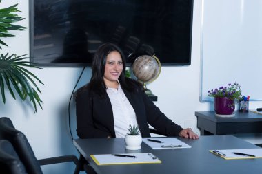 Ofisteki bir masada otururken bilgisayarın üzerinde çalışan güzel esmer kadın.