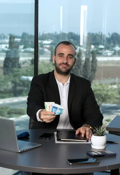 Takım elbiseli kendine güvenen bir işadamı bir sürü para tutuyor ILS şekelleri. Zaman yatırımı, maaş, kredi ve rüşvet konsepti. Başarı kariyer serveti. Reklam için boşluk kopyala.