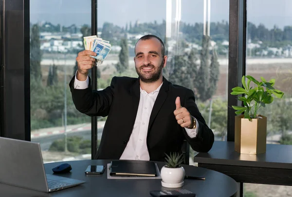 Takım elbiseli, kendine güvenen bir işadamı elinde ILS şekel para tutuyor ve zaman yatırım konseptini gösteriyor. Başarı kariyer serveti. Reklam için boşluk kopyala.