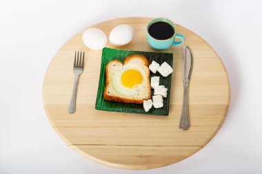 Seramik kasede tostlu sahanda yumurta, bir fincan espresso ve ahşap kesme tahtasında haşlanmış yumurta kırpma yolu ile izole edilmiş beyaz arka plan. Tabakta dilimlenmiş peynir.