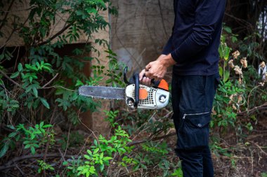 Tahta testeresi hareket halindeyken yakın çekim, talaş yana doğru uçar. Elektrikli testereli adam. Tehlikeli bir iş. Güçlü elektrikli testere. Oduncu testereyi tut. Bahçıvan oduncu ekipmanı..