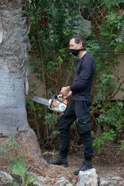 Man with the chainsaw. Dangerous job. Powerful chainsaw. Lumberjack hold chainsaw. Gardener lumberjack equipment. Working in the garden near home during quarantine.