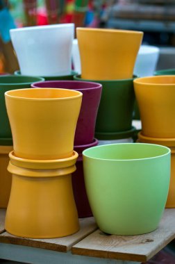 Bir bahçe mağazasında birçok renkli tencere var. Dekoratif plastik saksılar. Plastik geri dönüşümü. Bahçe işleri için plastik çatal bıçak üretimi