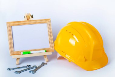 Sarı güvenlik kaskı, mini sehpa ve beyaz arka planda izole edilmiş metal anahtarlar. Tasarım için alanı kopyala. Endüstriyel işçiler veya inşaat alanı güvenlik ekipmanları kavramı.