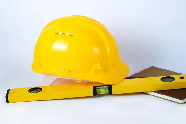 Construction concept. Yellow safety helmet, notepad and water level lind (bubble spirit level tools) to check balance in construction sites. Business and industry concept. Copy space for design.