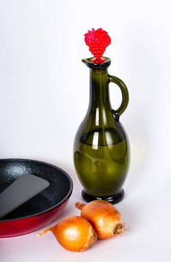 Sebze yağı, iki tam soğan, masada karıştırmak için kırmızı kızartma tavası ve spatula. Seçici odaklanma. Mutfak aletleri. Mutfak eşyaları. Yemek takımı. Yemek hazırlayın. Tasarım, pankart, kopyalama alanı. 