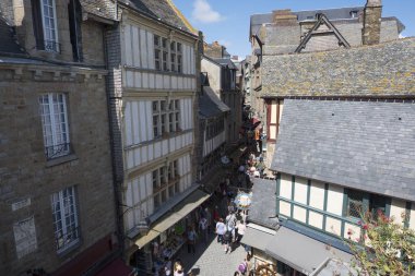 Mont Saint Michel, Fransa - 17 Ağustos 2018: Turist mağazaları ve restoranları, tarihi Mont Saint-Michel ile kaplı dar bir sokakta yürümek. Normandy, Fransa
