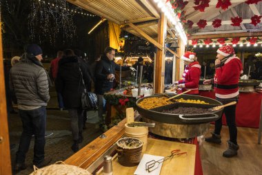 Poznan, Polonya - 04 Aralık 2018: İki saleswomen ile sıcak yemek satan bir Noel büfe içinde. Poznan içinde belgili tanımlık Noel çarşı sakinleri ve turistler ziyaret edin. Polonya
