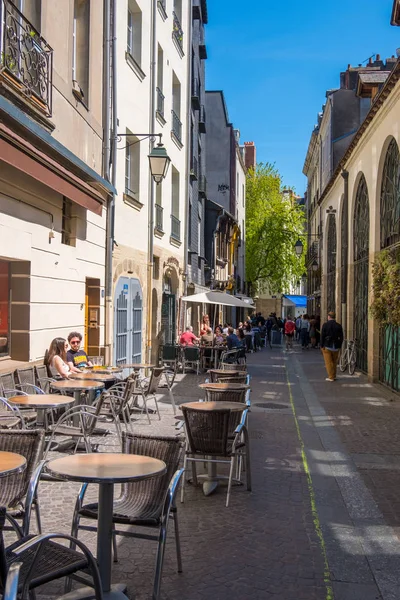 Personas sentadas en un café al aire libre en una calle peatonal de Nantes, Francia — Foto de Stock