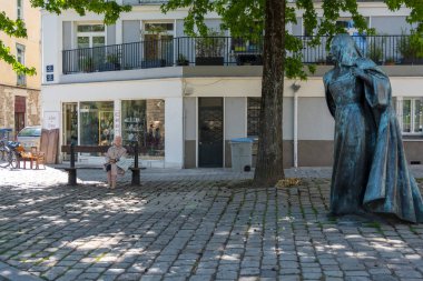 Fransa Kraliçesi Anne de Bretagne'in heykelinin yanındaki yeşil ağaçların altında bankta oturan kıdemli bir kadın. Nantes Fransa