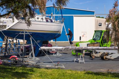 Bir adam rıhtımda bir yata hizmet etmekle meşgul.