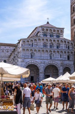 Lucca, İtalya - 17 Ağustos 2019: Lucca 'nın tarihi merkezindeki San Martino katedrali önünde bir turist ve yerel halk bit pazarında geziniyor