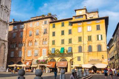Lucca, İtalya - 17 Ağustos 2019: Turistler, Lucca, Toskana 'nın tarihi merkezindeki Piazza San Michele meydanında, Foro' daki San Michele kilisesinin yakınında yürüyorlar.