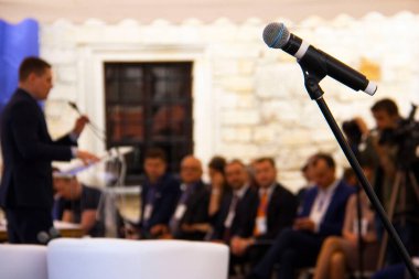 Yatırım Forumu: Sahnede seyircilere hitap eden bir iş adamının arka planındaki mikrofon.