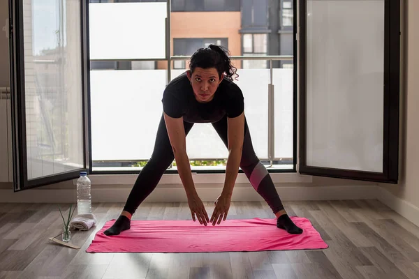 Kafkasyalı kız elinde dizüstü bilgisayarla oturma odasında yoga yapıyor.