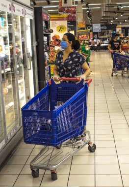 10 Haziran 2020. Madrid Spaid. Beyaz kadın kendini virüslerden korumak için hijyen kurallarına uyan mavi elbiseli bir süpermarkette alışveriş yapıyor..