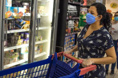 10 Haziran 2020. Madrid Spaid. Beyaz kadın kendini virüslerden korumak için hijyen kurallarına uyan mavi elbiseli bir süpermarkette alışveriş yapıyor..