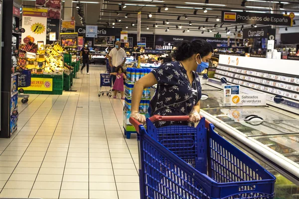 10 Haziran 2020. Madrid Spaid. Beyaz kadın kendini virüslerden korumak için hijyen kurallarına uyan mavi elbiseli bir süpermarkette alışveriş yapıyor..