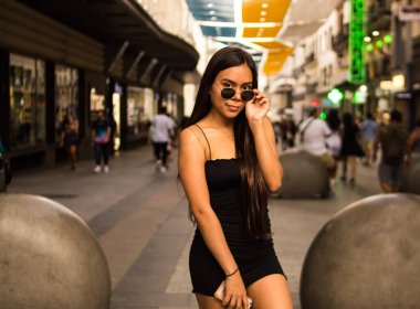 Bir yaz günü şehirde gezinirken poz veren genç İspanyol kadının seçici odak noktası