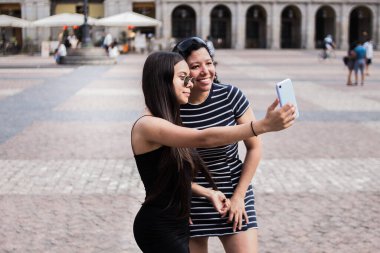 Şehirdeki bir meydanda elektronik aletlerini kullanan genç kadınların seçici odak noktası