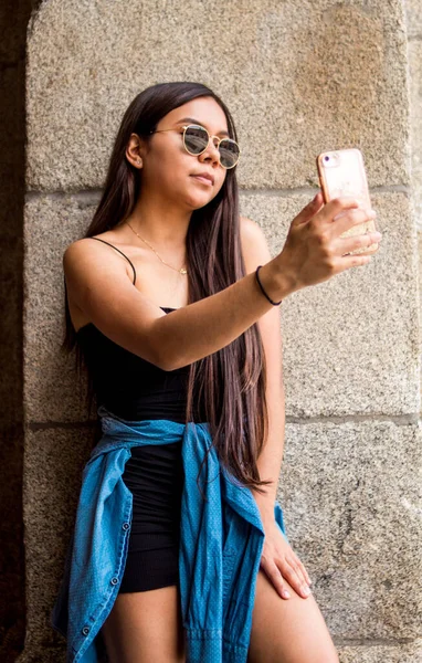 Şehirde dolaşırken selfie çeken genç bir İspanyol kadının seçici odak noktası.