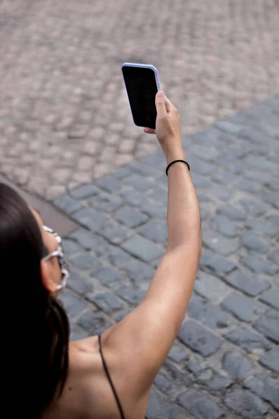 Akıllı telefonuyla selfie çekerken tıbbi maske takan genç İspanyol kadının seçici odak noktası.