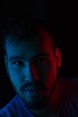 Yüzünde mavi ve kırmızı ışıklar olan beyaz bir adamın seçici odak portresi.