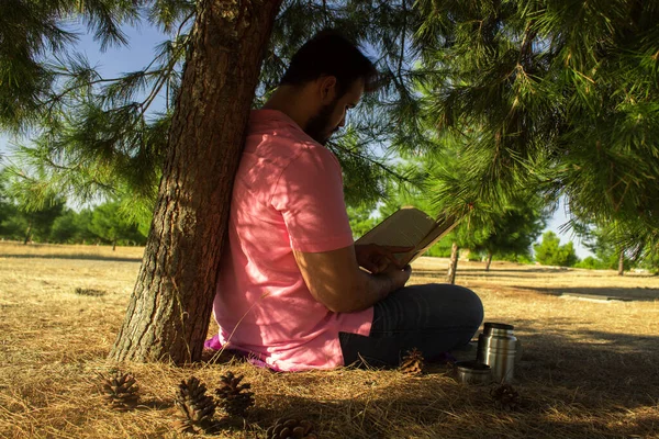 Biały Mężczyzna Dżinsach Różowej Koszuli Siedzący Obok Drzewa Lesie Czytający — Zdjęcie stockowe