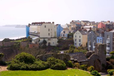 Castle Hill 'den manzara, bahar güneşinde kayalıklardaki pastel renkli evler, Tenby, Pembrokeshire, Galler, İngiltere