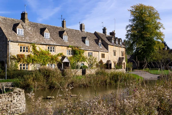 Aşağı Katliam, Gloucestershire, İngiltere 'nin nehir kenarındaki sakin Cotswold kulübelerinde sonbahar güneşi.