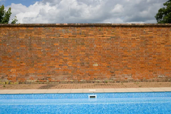 Gammal Röd Tegelvägg Kontrasterar Mot Blå Himmel Och Pool — Stockfoto