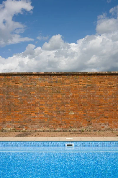 青い空とスイミングプールと対照的に古い赤レンガの壁 — ストック写真